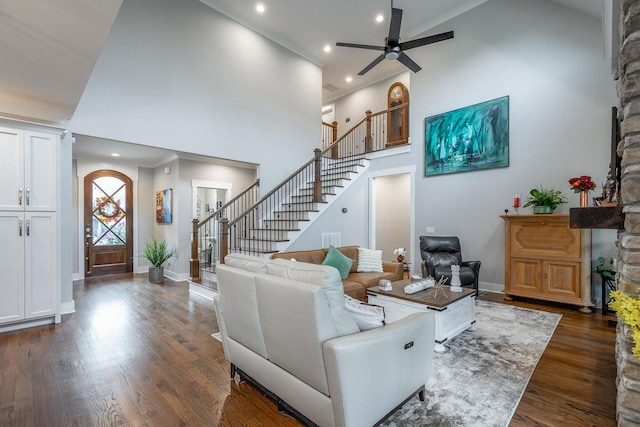 living room with dark hardwood / wood-style floors, a fireplace, high vaulted ceiling, ornamental molding, and ceiling fan