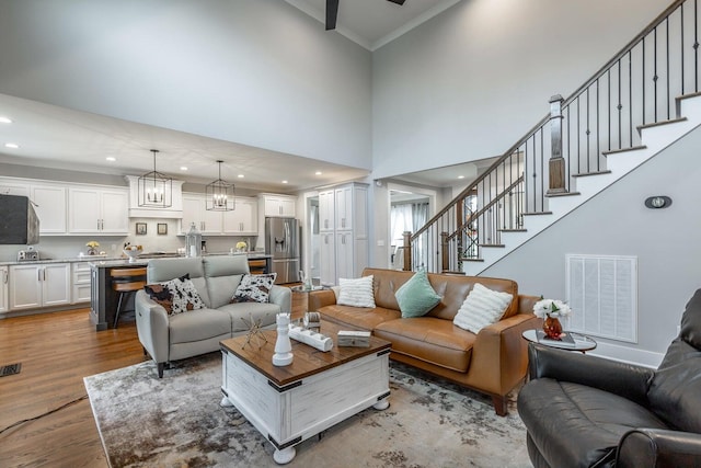 living room featuring light hardwood / wood-style flooring, a towering ceiling, and ornamental molding