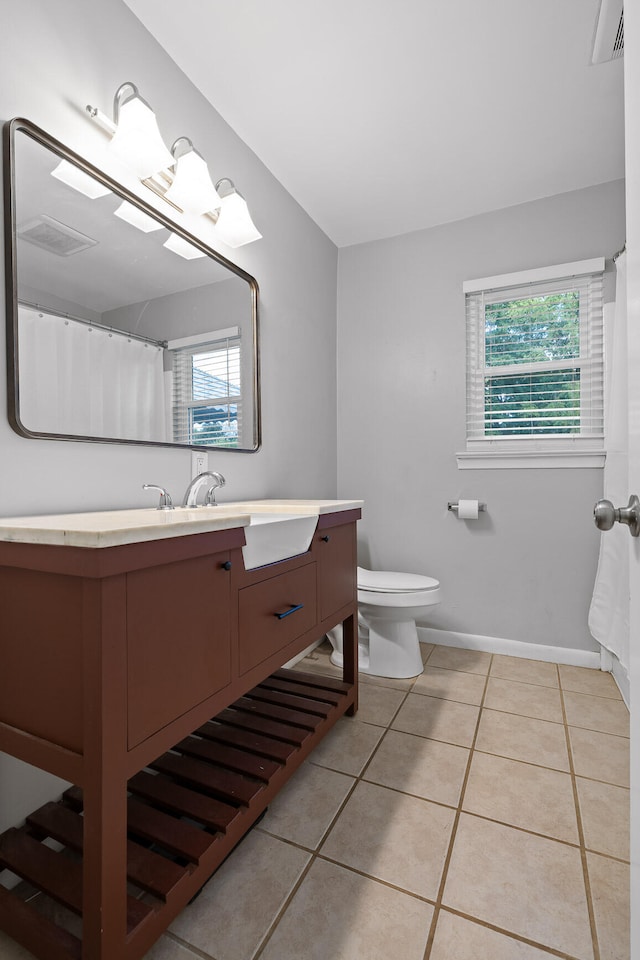 bathroom with tile patterned flooring, vanity, toilet, and a wealth of natural light