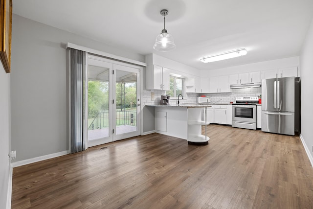 kitchen featuring light stone counters, white cabinets, kitchen peninsula, hanging light fixtures, and appliances with stainless steel finishes