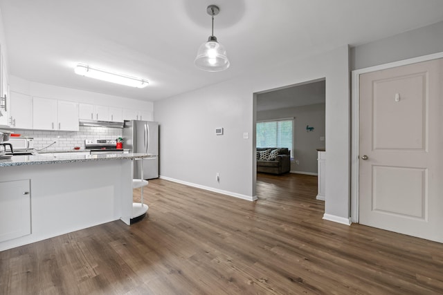 kitchen with hanging light fixtures, dark wood-type flooring, white cabinetry, appliances with stainless steel finishes, and light stone countertops