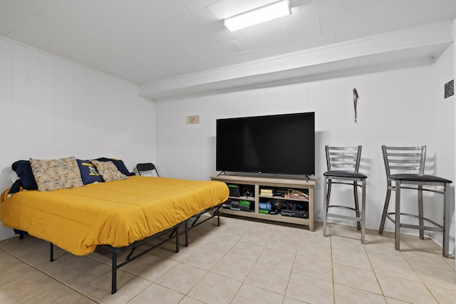 bedroom with wooden walls and light tile patterned floors