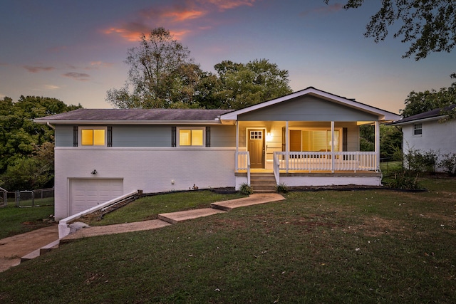 view of front of property featuring a yard, covered porch, and a garage