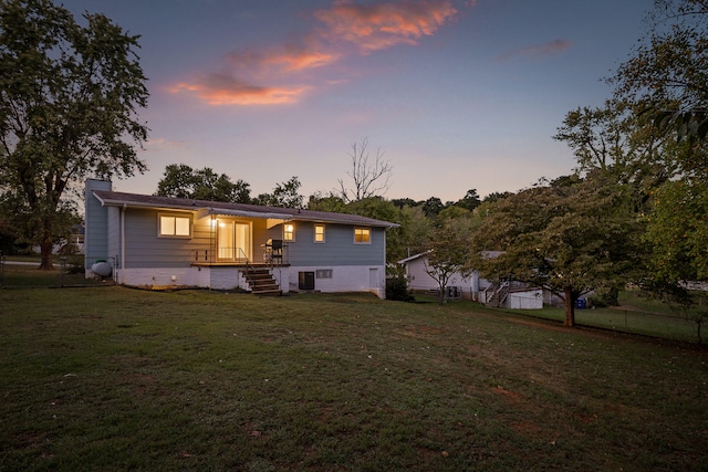 back house at dusk featuring cooling unit and a lawn