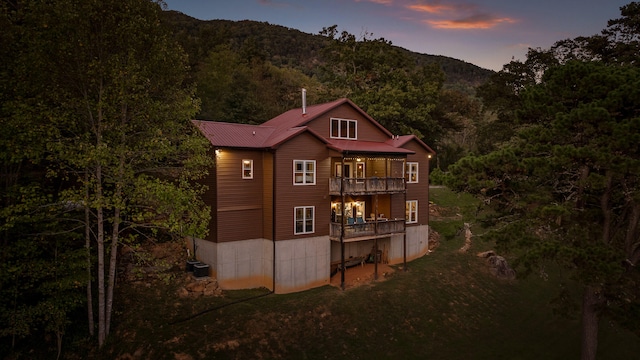 back house at dusk featuring a mountain view and a balcony