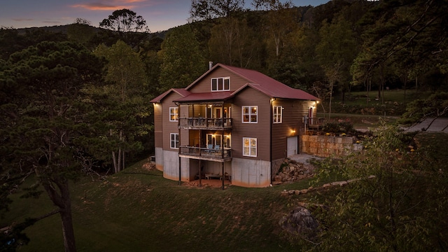 back house at dusk with a balcony and a garage