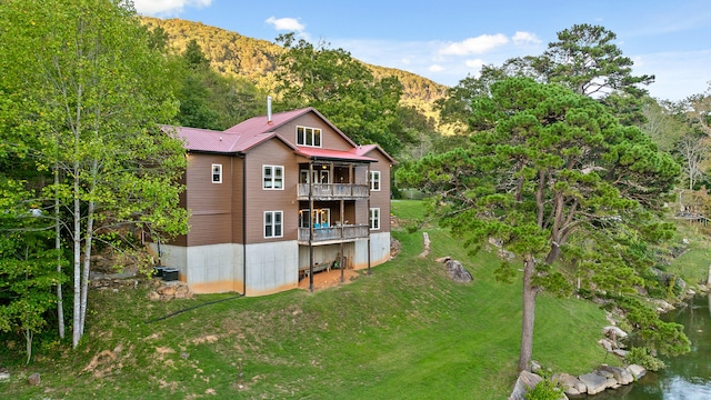 rear view of property featuring a balcony, a lawn, and a mountain view