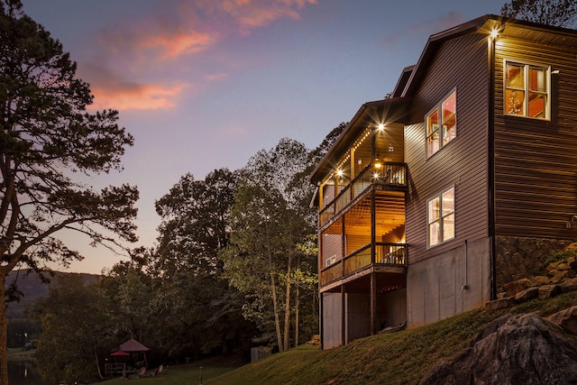 property exterior at dusk with a yard and a balcony