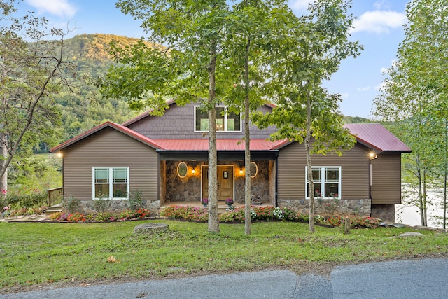 view of front facade with a front lawn, a mountain view, and covered porch