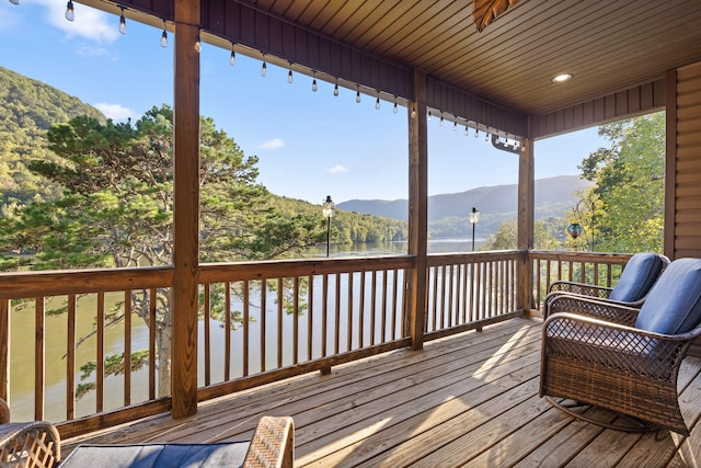 wooden deck with a water and mountain view