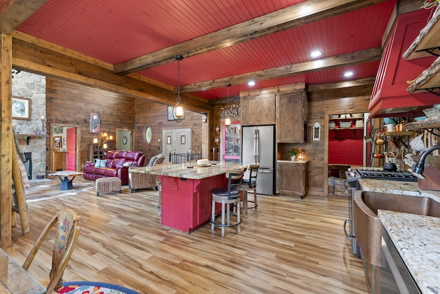 kitchen featuring appliances with stainless steel finishes, a center island, beam ceiling, and light hardwood / wood-style flooring