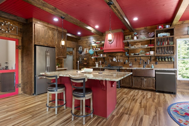 bar featuring light hardwood / wood-style floors, pendant lighting, beam ceiling, light stone counters, and appliances with stainless steel finishes