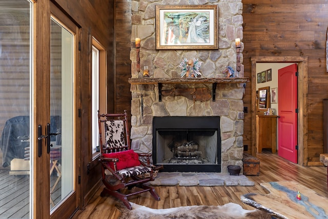 living room featuring a stone fireplace, wood walls, and hardwood / wood-style floors