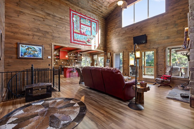 living room featuring high vaulted ceiling, wood walls, wood ceiling, and wood-type flooring