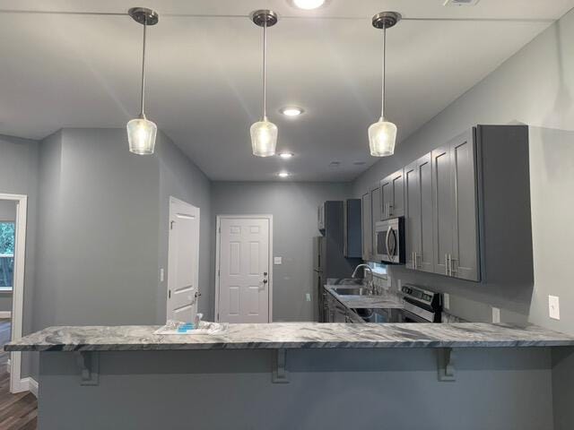 kitchen with kitchen peninsula, stainless steel appliances, and gray cabinetry