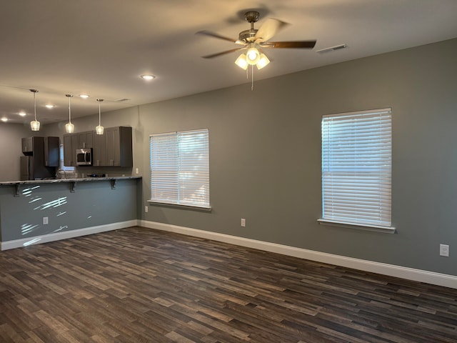 kitchen with ceiling fan, a breakfast bar area, kitchen peninsula, and dark hardwood / wood-style flooring