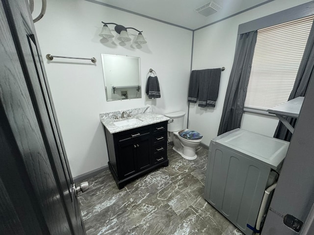 bathroom with vanity, toilet, and washer / dryer