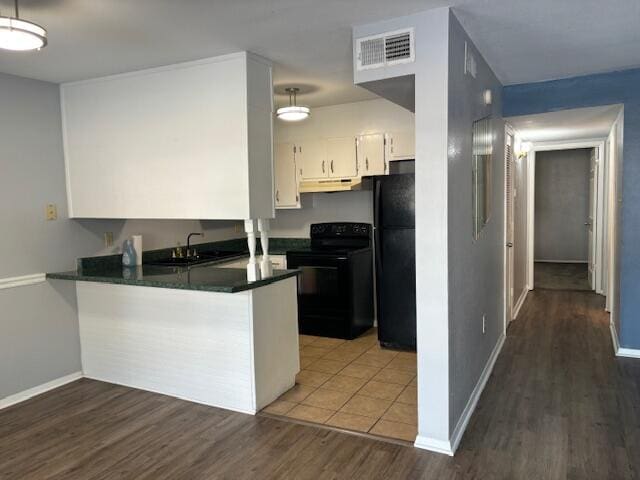 kitchen with sink, kitchen peninsula, white cabinetry, black appliances, and dark hardwood / wood-style floors