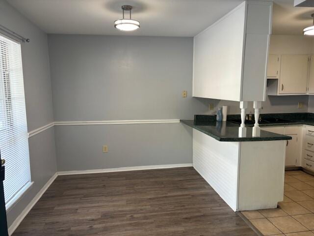 kitchen featuring white cabinets, kitchen peninsula, and dark hardwood / wood-style floors