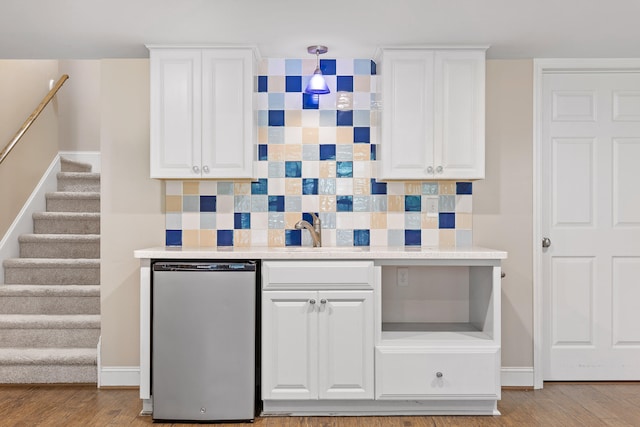 kitchen featuring dishwasher, light hardwood / wood-style flooring, backsplash, and white cabinetry