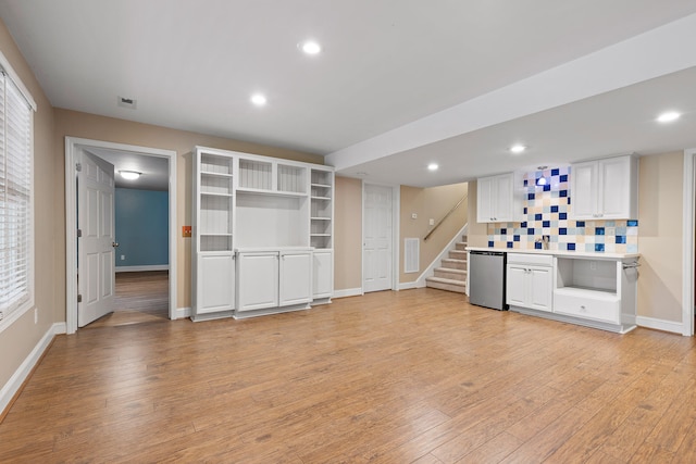 kitchen featuring white cabinets, dishwasher, light wood-type flooring, and decorative backsplash