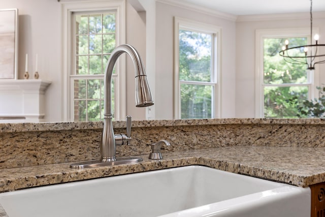 interior details featuring an inviting chandelier, ornamental molding, sink, and decorative light fixtures