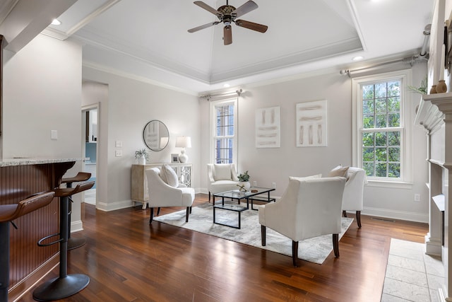 living room featuring ceiling fan, hardwood / wood-style flooring, a raised ceiling, and crown molding