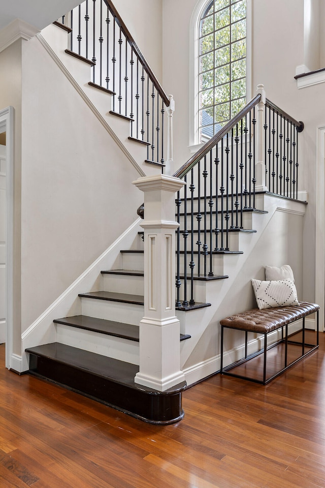 stairway with hardwood / wood-style floors and crown molding