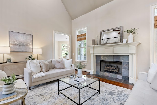 living room with a baseboard radiator, a tiled fireplace, hardwood / wood-style floors, and high vaulted ceiling