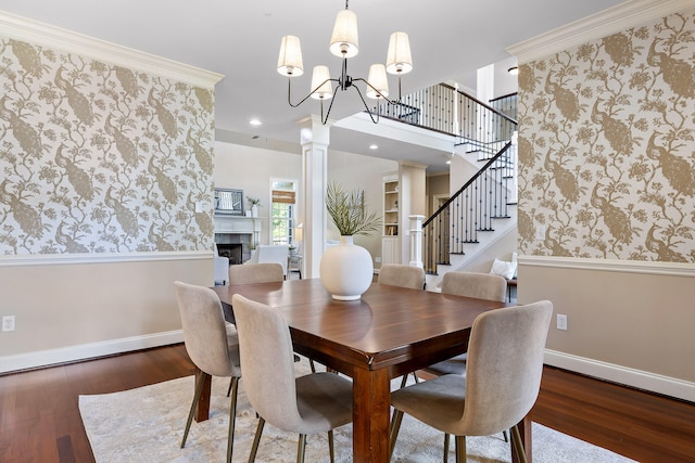 dining space with a notable chandelier, decorative columns, hardwood / wood-style floors, and crown molding