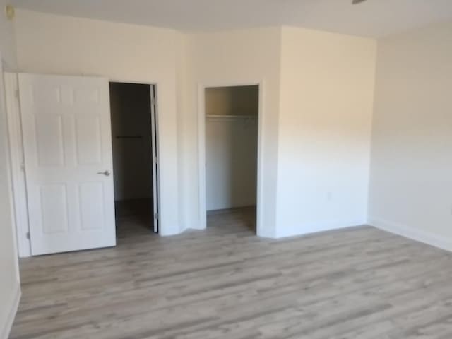 unfurnished bedroom with light wood-type flooring, a closet, and a walk in closet