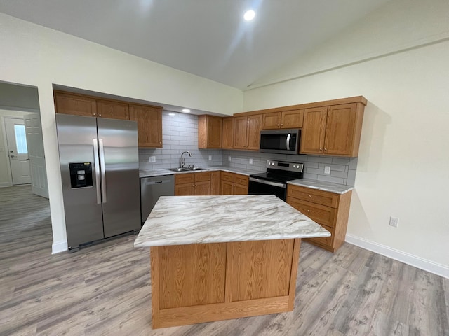 kitchen with tasteful backsplash, sink, vaulted ceiling, light hardwood / wood-style flooring, and appliances with stainless steel finishes