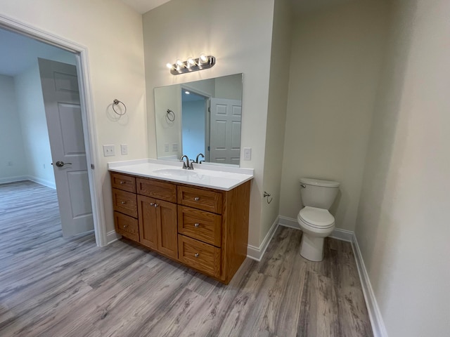 bathroom with wood-type flooring, vanity, and toilet