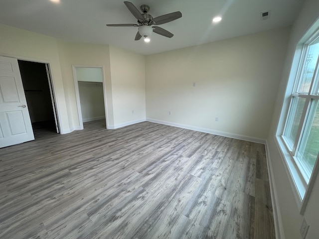 unfurnished bedroom with a closet, light hardwood / wood-style floors, ceiling fan, and a walk in closet