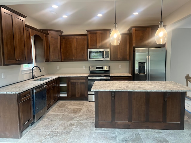 kitchen featuring sink, light stone countertops, decorative light fixtures, and stainless steel appliances