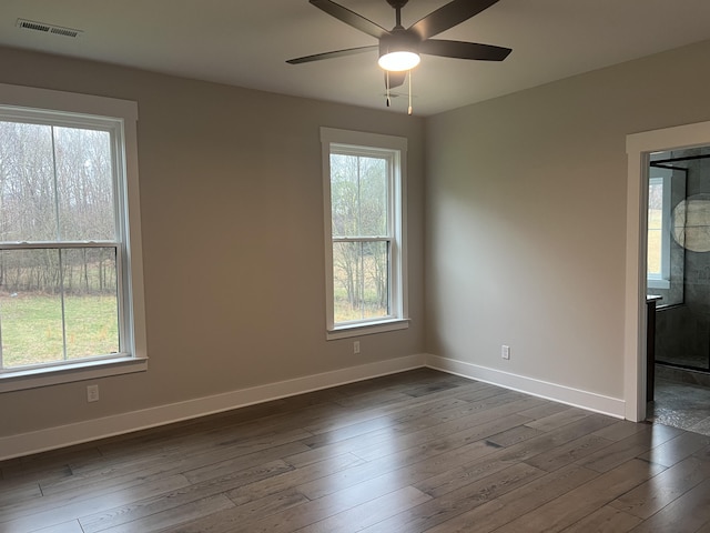 empty room with ceiling fan, plenty of natural light, and dark hardwood / wood-style floors