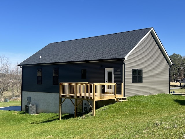 rear view of property with a wooden deck, central air condition unit, and a lawn