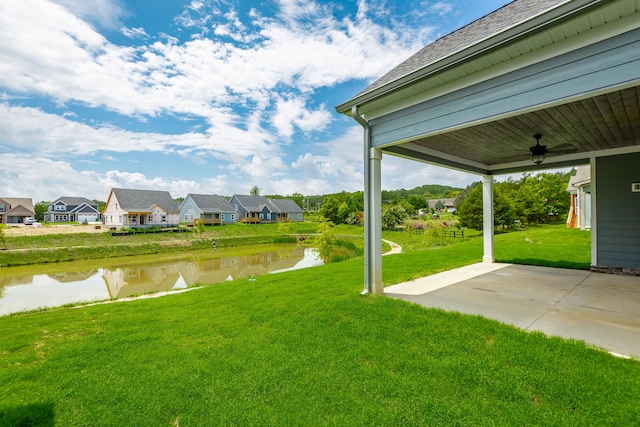 view of yard featuring a water view, ceiling fan, and a patio