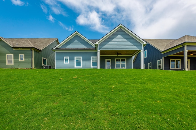 back of property featuring ceiling fan and a yard