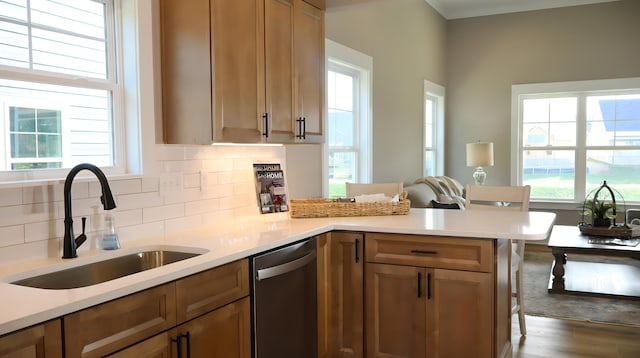 kitchen featuring light hardwood / wood-style floors, kitchen peninsula, sink, tasteful backsplash, and stainless steel dishwasher