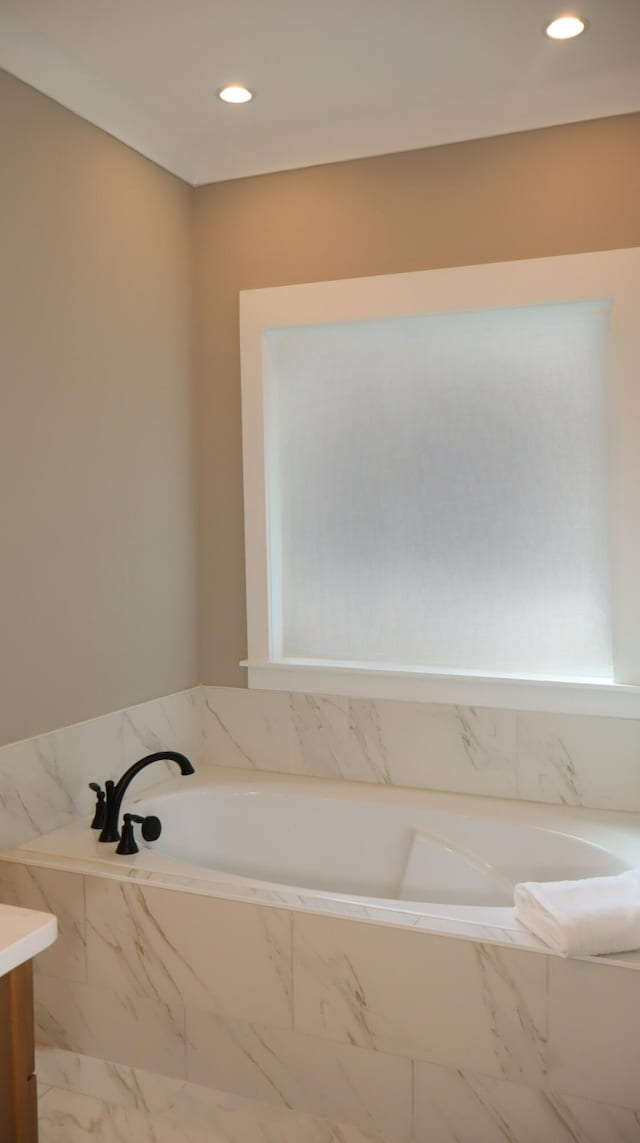 bathroom with vanity and tiled bath