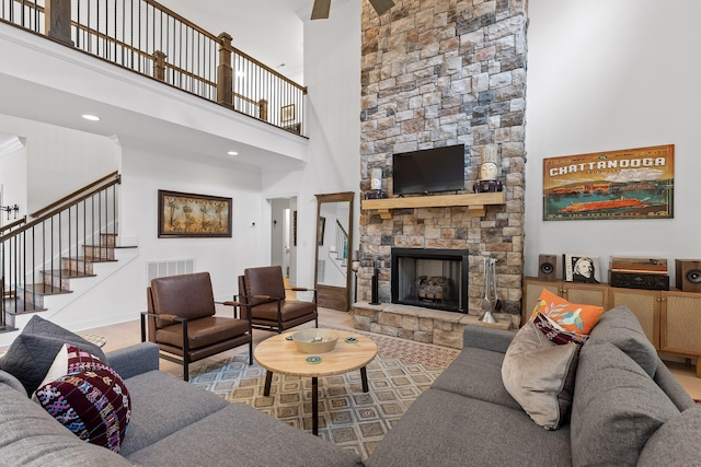 living room featuring ceiling fan, a fireplace, and a high ceiling