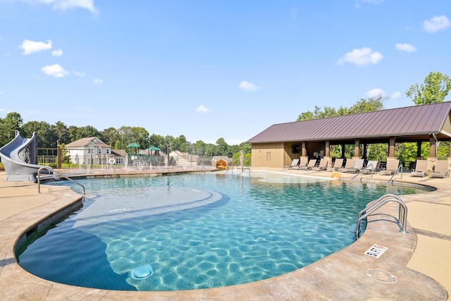 view of swimming pool with a patio and a water slide