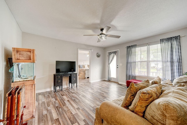 living room featuring a textured ceiling, light wood-type flooring, and ceiling fan