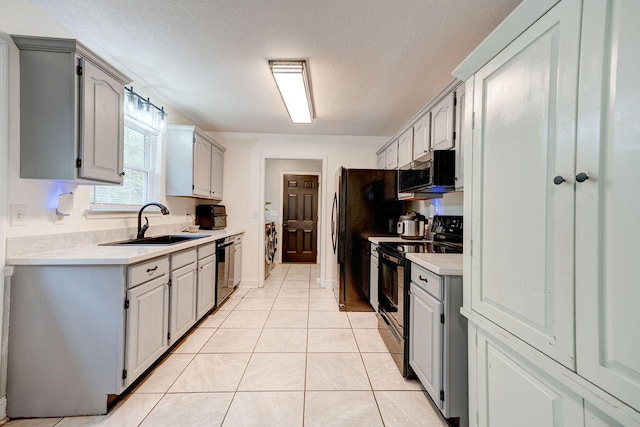 kitchen with gray cabinetry, sink, appliances with stainless steel finishes, light tile patterned floors, and a textured ceiling