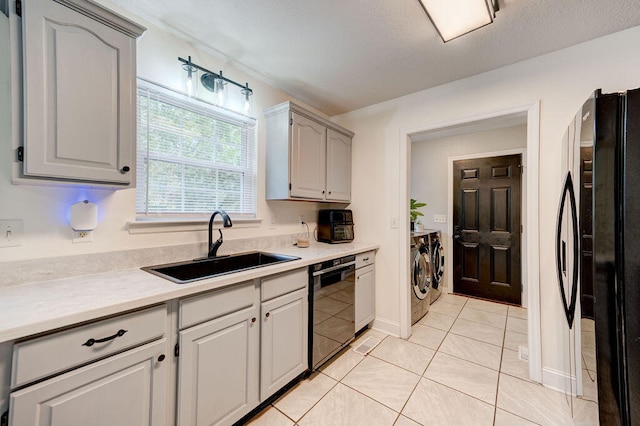 kitchen with black appliances, sink, light tile patterned flooring, washing machine and dryer, and gray cabinets