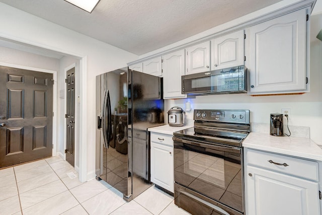 kitchen with black appliances, light tile patterned floors, and a textured ceiling