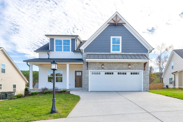 view of front of home with covered porch, a garage, and a front lawn