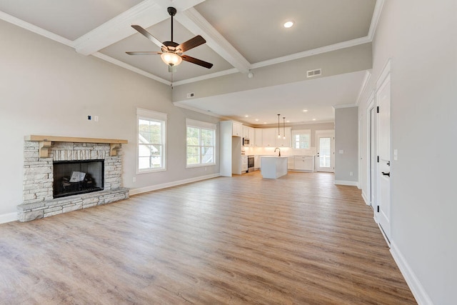 unfurnished living room featuring beam ceiling, light hardwood / wood-style floors, ceiling fan, and ornamental molding