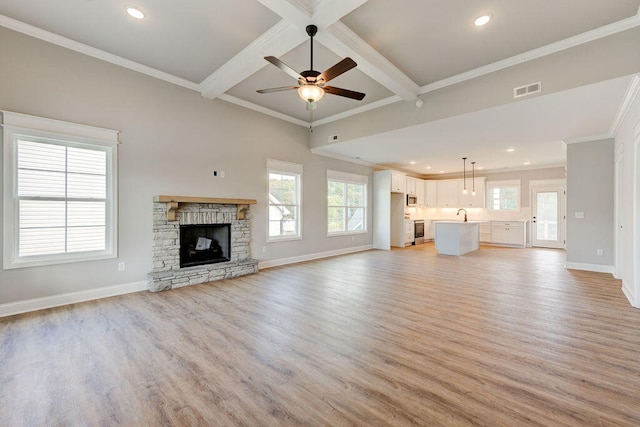 unfurnished living room featuring beam ceiling, light hardwood / wood-style flooring, and a healthy amount of sunlight